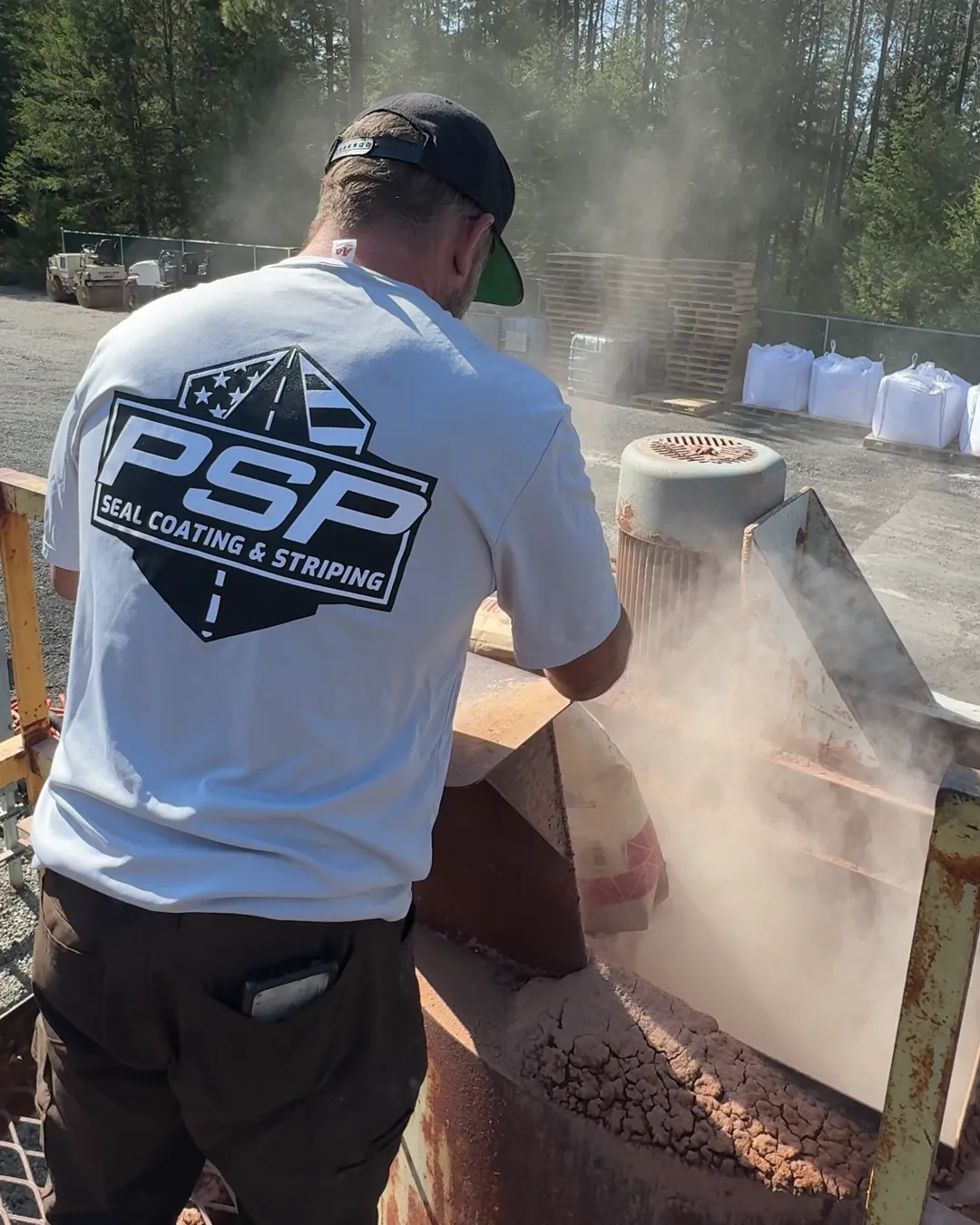 A bag of clay tipped by hand into the mixer hopper, the PSP badge on the back of the shirt.